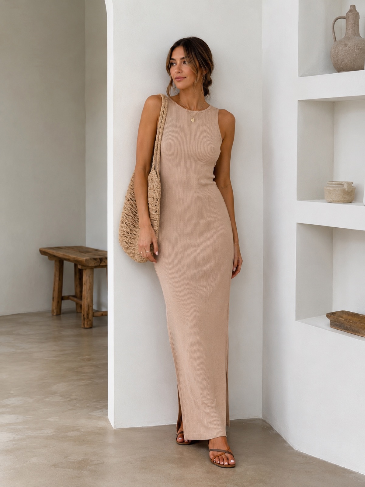 Vestido longo canelado em tom areia junto a uma parede clara